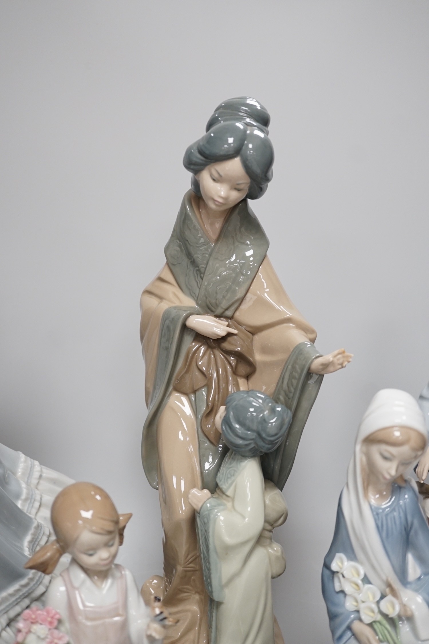Seven Lladro and two Nao porcelain figures together with another, stuck to base so mark can’t be seen. Tallest 38cm